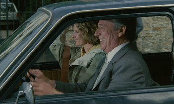 Movie still from “Waiter!” (1983), directed by Claude Sautet – A man and a woman sitting in the drivers seat of a car; Medium shot, Over the shoulder angle