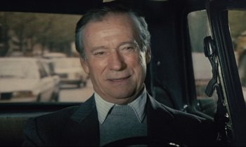 Movie still from “Waiter!” (1983), directed by Claude Sautet – An older man wearing a suit and tie in a car; Close Up shot, High angle