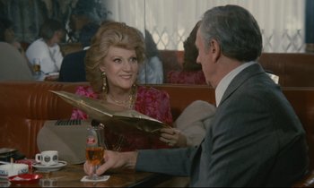 Movie still from “Waiter!” (1983), directed by Claude Sautet – An older man and woman sitting at a table with drinks; Medium shot, Over the shoulder angle