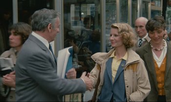 Movie still from “Waiter!” (1983), directed by Claude Sautet – A man and a woman shaking hands in front of a store window; Medium shot, Over the shoulder angle