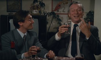 Movie still from “Waiter!” (1983), directed by Claude Sautet – Two men sitting at a dinner table drinking wine; Medium shot, High angle