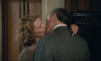 Movie still from “Waiter!” (1983), directed by Claude Sautet – A man and a woman kissing each other in front of a door; Close Up shot, Over the shoulder angle