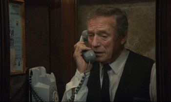 Movie still from “Waiter!” (1983), directed by Claude Sautet – An older man talking on a phone while wearing a suit and tie; Close Up shot, High angle