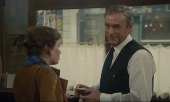 Movie still from “Waiter!” (1983), directed by Claude Sautet – An older man and a young woman are talking to each other; Medium shot, Over the shoulder angle