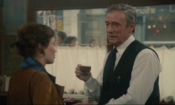Movie still from “Waiter!” (1983), directed by Claude Sautet – An older man and a young woman in a restaurant; Medium shot, Over the shoulder angle