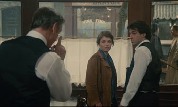 Movie still from “Waiter!” (1983), directed by Claude Sautet – A group of people standing in front of a window; Medium shot, Over the shoulder angle