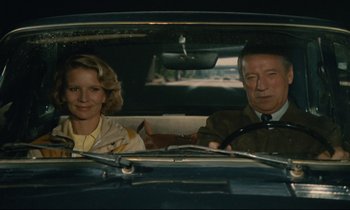 Movie still from “Waiter!” (1983), directed by Claude Sautet – A man and a woman sitting in the back seat of a car; Medium shot, High angle