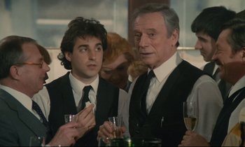 Movie still from “Waiter!” (1983), directed by Claude Sautet – A man and a woman are sitting at a table with wine glasses; Medium shot, Over the shoulder angle