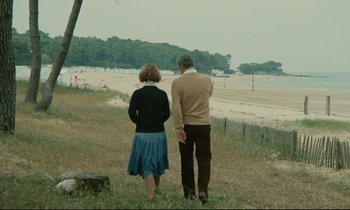 Movie still from “Waiter!” (1983), directed by Claude Sautet – A man and a woman standing on a beach; Wide shot, High angle