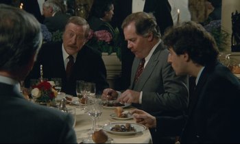 Movie still from “Waiter!” (1983), directed by Claude Sautet – A group of people sitting at a table eating food; Medium shot, Over the shoulder angle