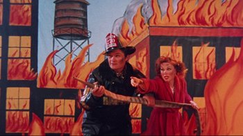 Movie still from “Waiting for Guffman” (1996), directed by Christopher Guest – A man and a woman holding a fire hydrant and a fire hydrant; Medium shot, High angle
