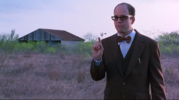 Movie still from “Waiting for Guffman” (1996), directed by Christopher Guest – A man in a suit and bow tie holding a fork; Medium shot, Over the shoulder angle