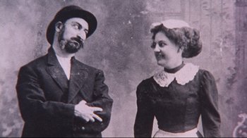 Movie still from “Waiting for Guffman” (1996), directed by Christopher Guest – An old photo of a man and a woman standing next to each other; Medium shot, Low angle