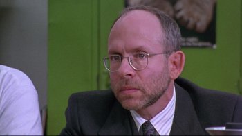 Movie still from “Waiting for Guffman” (1996), directed by Christopher Guest – A person wearing a suit and glasses; Close Up shot, Over the shoulder angle