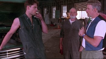 Movie still from “Waiting for Guffman” (1996), directed by Christopher Guest – A man smoking a cigarette while standing next to two other men; Medium shot, Low angle
