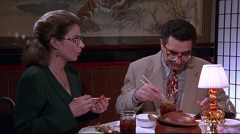 Movie still from “Waiting for Guffman” (1996), directed by Christopher Guest – A man and a woman sitting at a table with chopsticks in their hands; Medium shot, High angle