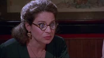 Movie still from “Waiting for Guffman” (1996), directed by Christopher Guest – A person wearing glasses and a green shirt; Close Up shot, Over the shoulder angle