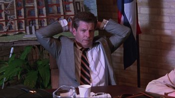 Movie still from “Waiting for Guffman” (1996), directed by Christopher Guest – A man sitting at a table with his hands behind his head; Medium shot, High angle