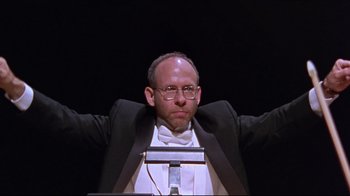 Movie still from “Waiting for Guffman” (1996), directed by Christopher Guest – A man in a suit and tie with his arms outstreched; Medium shot, Low angle