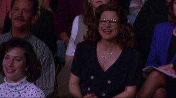 Movie still from “Waiting for Guffman” (1996), directed by Christopher Guest – A woman with glasses is sitting in front of a group of people; Medium shot, High angle
