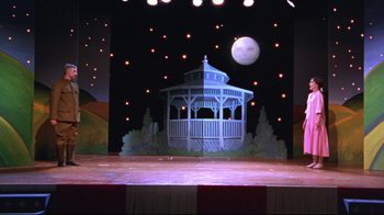 Movie still from “Waiting for Guffman” (1996), directed by Christopher Guest – A stage set with a gazebo and a full moon in the background; Wide shot, Low angle
