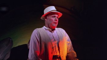 Movie still from “Waiting for Guffman” (1996), directed by Christopher Guest – A man wearing a white hat standing in front of a red light; Medium shot, Low angle