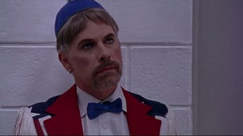 Movie still from “Waiting for Guffman” (1996), directed by Christopher Guest – A man with a beard wearing a red jacket and a blue hat; Close Up shot, Over the shoulder angle