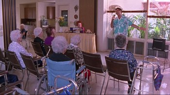 Movie still from “Waiting for Guffman” (1996), directed by Christopher Guest – A group of people sitting in a room with chairs; Wide shot, High angle