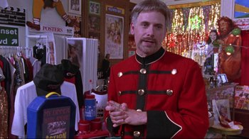 Movie still from “Waiting for Guffman” (1996), directed by Christopher Guest – A man in a red and black uniform standing in a room; Medium shot, Over the shoulder angle
