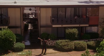 Movie still from “Waiting to Exhale” (1995), directed by Forest Whitaker – A man standing on the side of a building with his arms outstretched; Extreme Wide shot, High angle