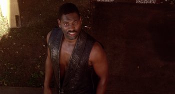 Movie still from “Waiting to Exhale” (1995), directed by Forest Whitaker – A man in a leather vest is looking at the camera; Close Up shot, High angle