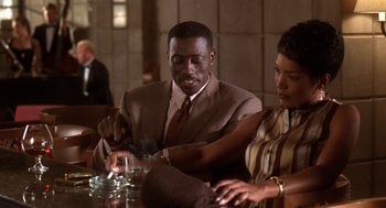 Movie still from “Waiting to Exhale” (1995), directed by Forest Whitaker – A man and a woman sitting at a dinner table; Medium shot, High angle