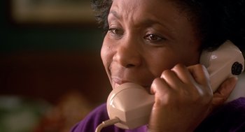 Movie still from “Waiting to Exhale” (1995), directed by Forest Whitaker – An older woman talking on a phone while wearing a purple shirt; Close Up shot, High angle