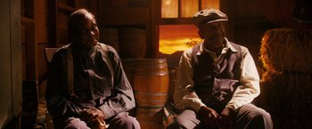Movie still from “Walk Hard: The Dewey Cox Story” (2007), directed by Jake Kasdan – Two men sitting next to each other in front of a barrel; Medium shot, Low angle