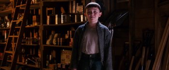 Movie still from “Walk Hard: The Dewey Cox Story” (2007), directed by Jake Kasdan – A young boy standing in front of shelves in a room; Medium shot, Low angle