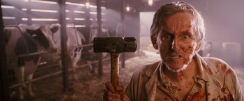 Movie still from “Walk Hard: The Dewey Cox Story” (2007), directed by Jake Kasdan – An old man holding a wooden hammer in a barn; Close Up shot, Low angle