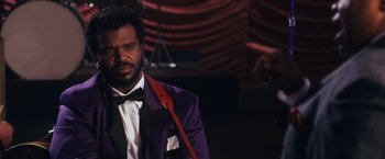 Movie still from “Walk Hard: The Dewey Cox Story” (2007), directed by Jake Kasdan – A man in a purple jacket and a red tie; Close Up shot, Over the shoulder angle