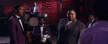 Movie still from “Walk Hard: The Dewey Cox Story” (2007), directed by Jake Kasdan – A man in a purple jacket and a man in a purple suit; Medium shot, Low angle