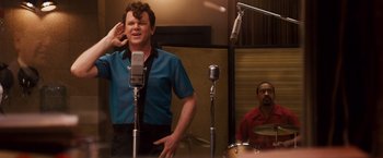 Movie still from “Walk Hard: The Dewey Cox Story” (2007), directed by Jake Kasdan – A man standing in front of microphones in a recording studio; Medium shot, Over the shoulder angle