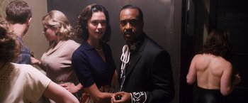 Movie still from “Walk Hard: The Dewey Cox Story” (2007), directed by Jake Kasdan – A man and a woman standing next to each other in front of an elevator; Medium shot, Over the shoulder angle