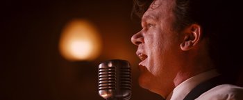 Movie still from “Walk Hard: The Dewey Cox Story” (2007), directed by Jake Kasdan – A person singing on a microphone; Close Up shot, Low angle