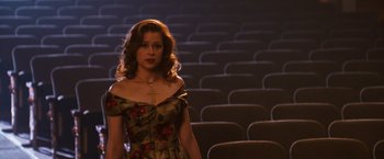 Movie still from “Walk Hard: The Dewey Cox Story” (2007), directed by Jake Kasdan – A woman standing in front of a row of seats; Medium shot, High angle