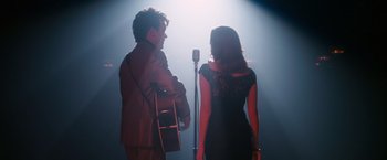 Movie still from “Walk Hard: The Dewey Cox Story” (2007), directed by Jake Kasdan – A man and a woman sing into microphones; Medium shot, Over the shoulder angle