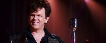 Movie still from “Walk Hard: The Dewey Cox Story” (2007), directed by Jake Kasdan – A person with a microphone; Close Up shot, Over the shoulder angle