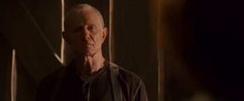 Movie still from “Walk Hard: The Dewey Cox Story” (2007), directed by Jake Kasdan – An older man wearing a black shirt and a black tie; Close Up shot, Low angle