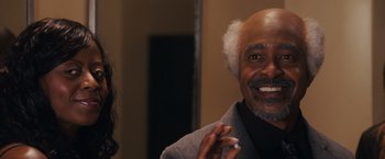 Movie still from “Walk Hard: The Dewey Cox Story” (2007), directed by Jake Kasdan – An older man and a young woman are smiling for the camera; Close Up shot, Over the shoulder angle
