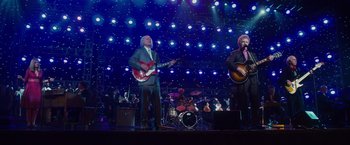 Movie still from “Walk Hard: The Dewey Cox Story” (2007), directed by Jake Kasdan – A couple of people on a stage with guitars; Wide shot, Low angle