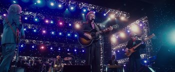 Movie still from “Walk Hard: The Dewey Cox Story” (2007), directed by Jake Kasdan – A man with a guitar on a stage; Wide shot, Low angle