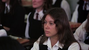 Movie still from “Walkabout” (1971), directed by Nicolas Roeg – A young woman sitting in front of other students; Close Up shot, Over the shoulder angle