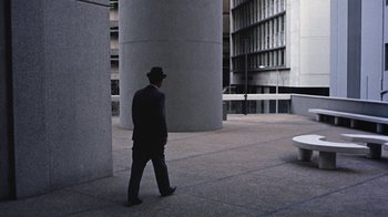 Movie still from “Walkabout” (1971), directed by Nicolas Roeg – A man wearing a hat walking in front of a tall building; Extreme Wide shot, High angle